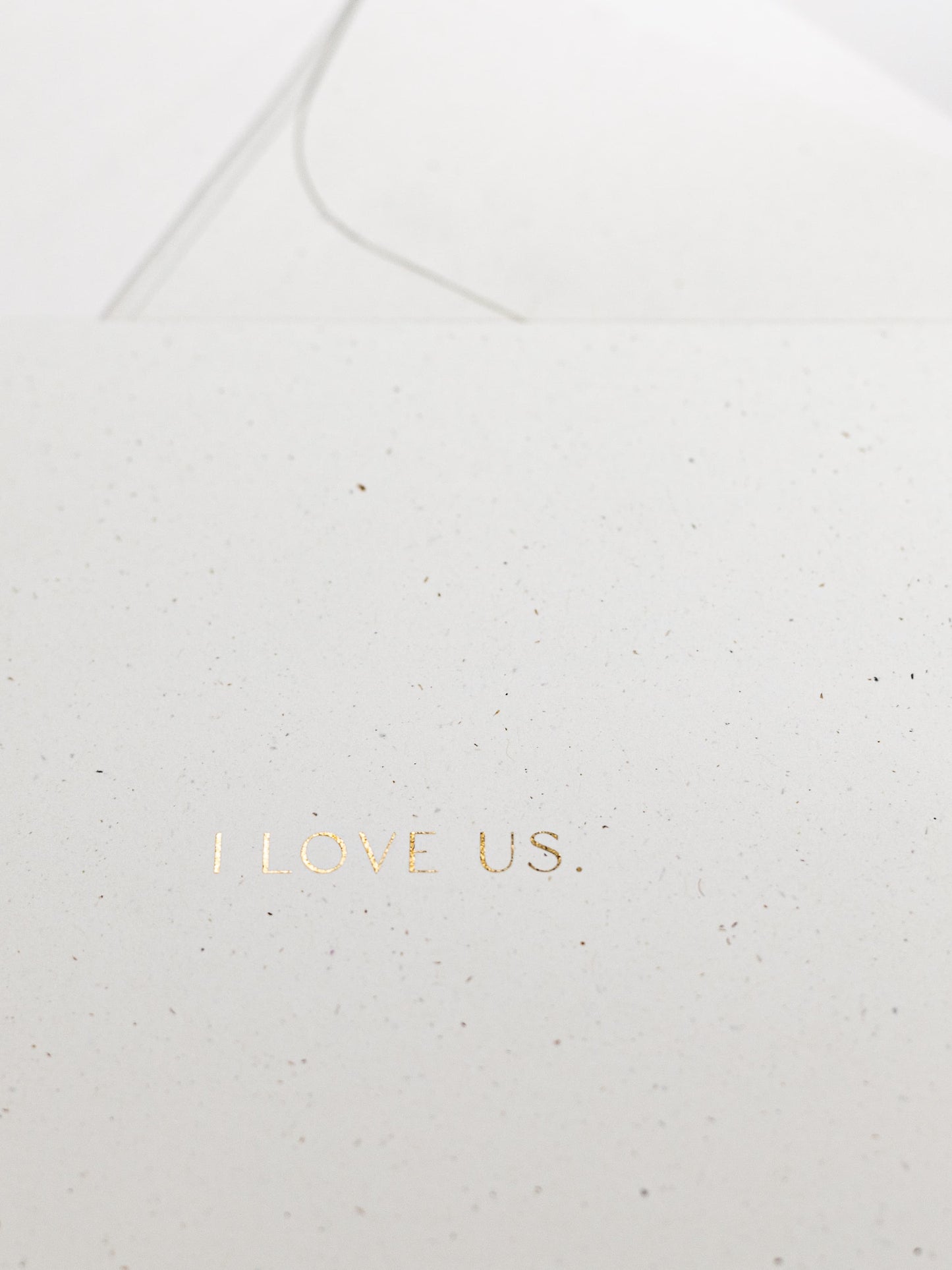 Detailansicht von weisser Karte zum Thema Liebe mit goldener Schrift „I LOVE US“ | Studio Wiis