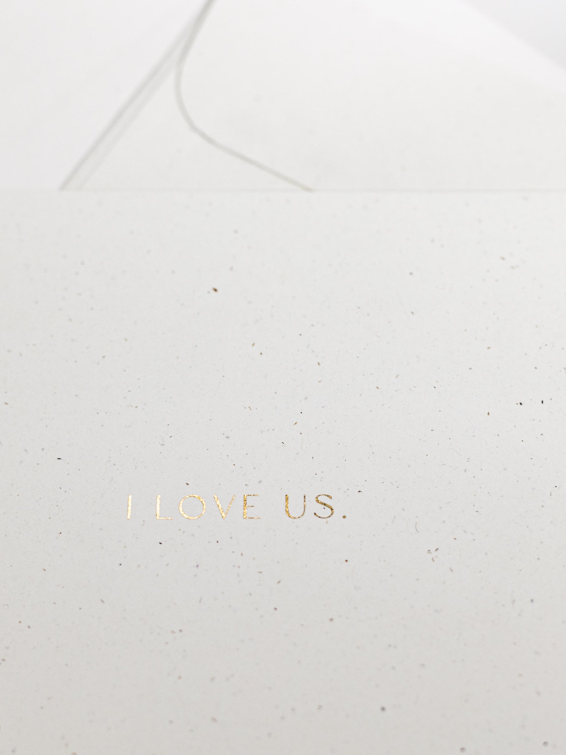 Detailansicht von weisser Karte zum Thema Liebe mit goldener Schrift „I LOVE US“ | Studio Wiis