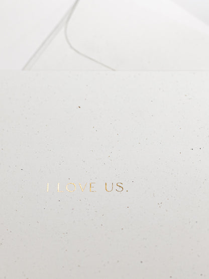 Detailansicht von weisser Karte zum Thema Liebe mit goldener Schrift „I LOVE US“ | Studio Wiis