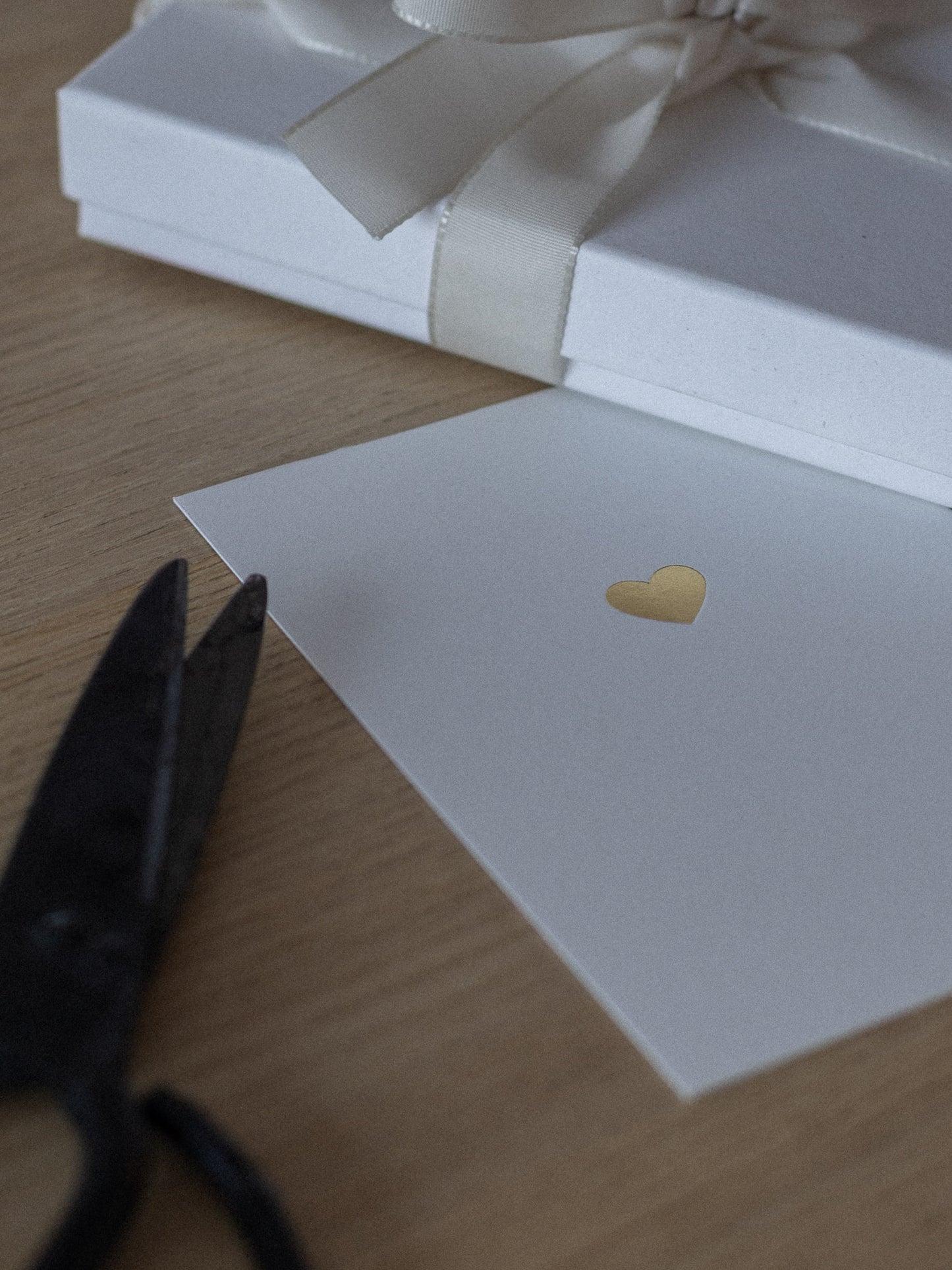Geprägte Karte mit goldenem Herz liegt neben Geschenk | Studio Wiis