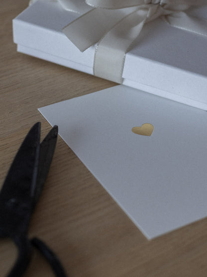 Geprägte Karte mit goldenem Herz liegt neben Geschenk | Studio Wiis