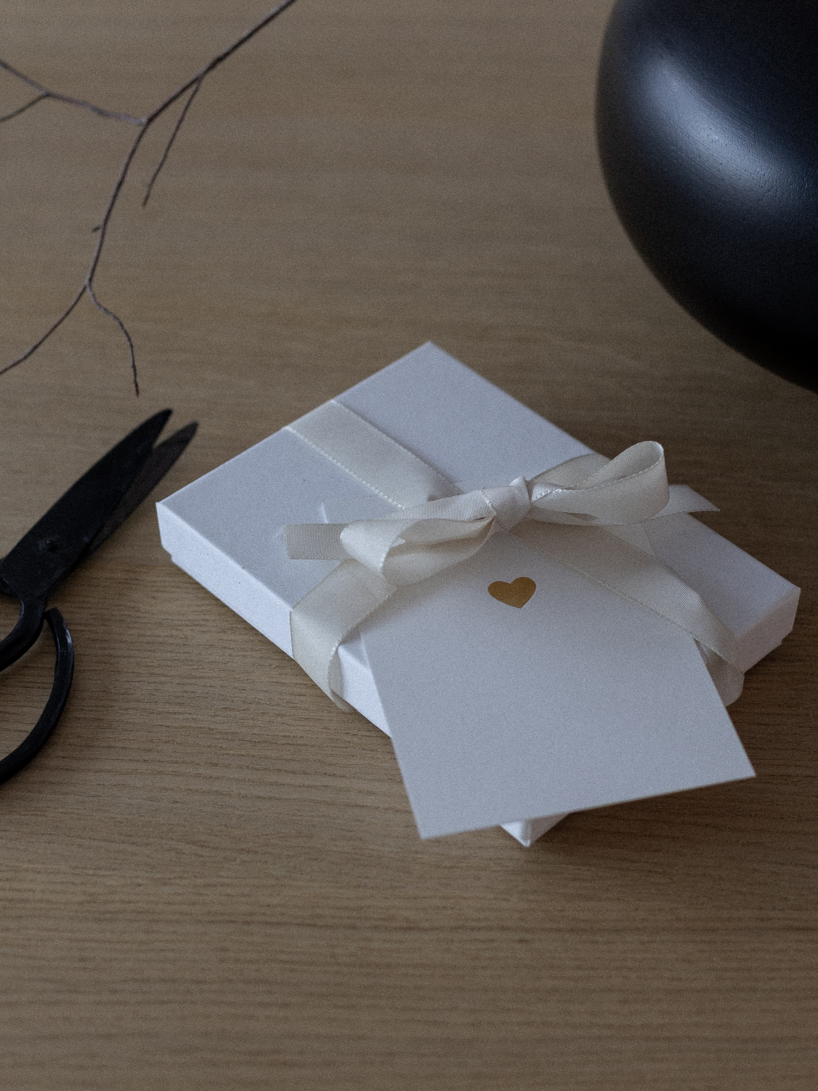 Valentinskarte mit Herz in Gold liegt auf Valentinsgeschenk mit Schleife | Studio Wiis