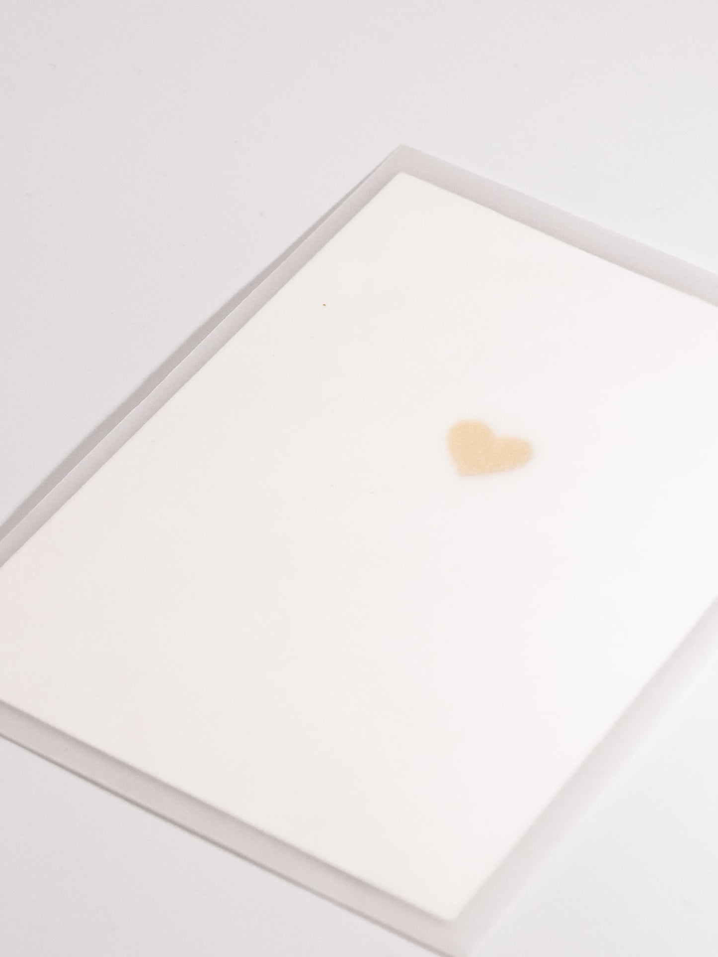Schlichte weisse Karte mit goldem Herz in transparentem Couvert